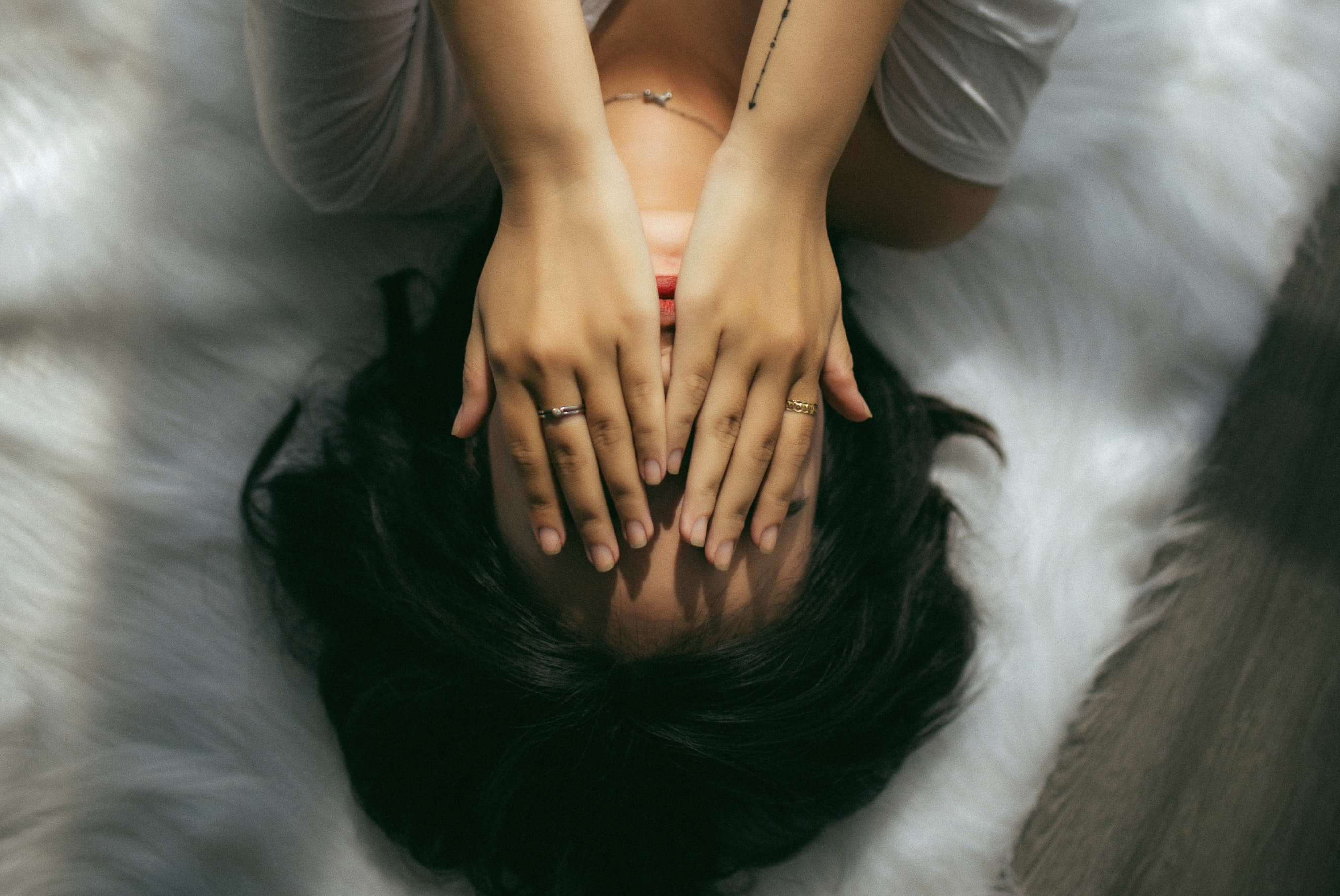 woman upside-down laying in bed, hands over face