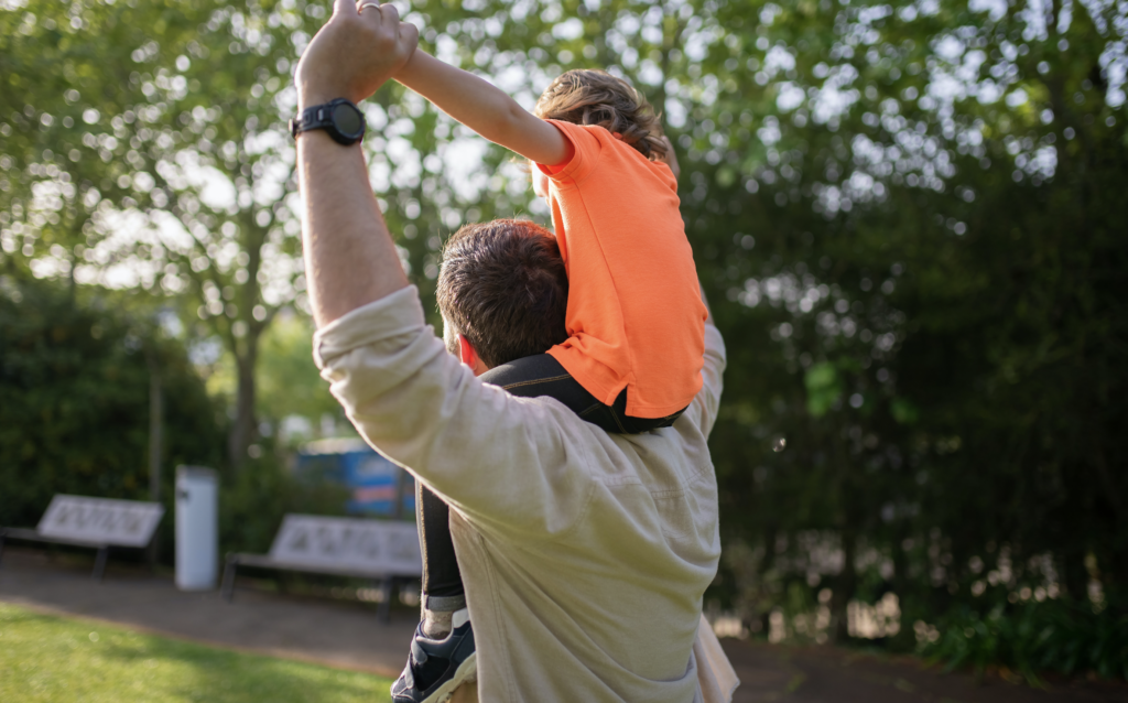 Read Sammy’s Story: a child riding on an adult’s shoulders outdoors.