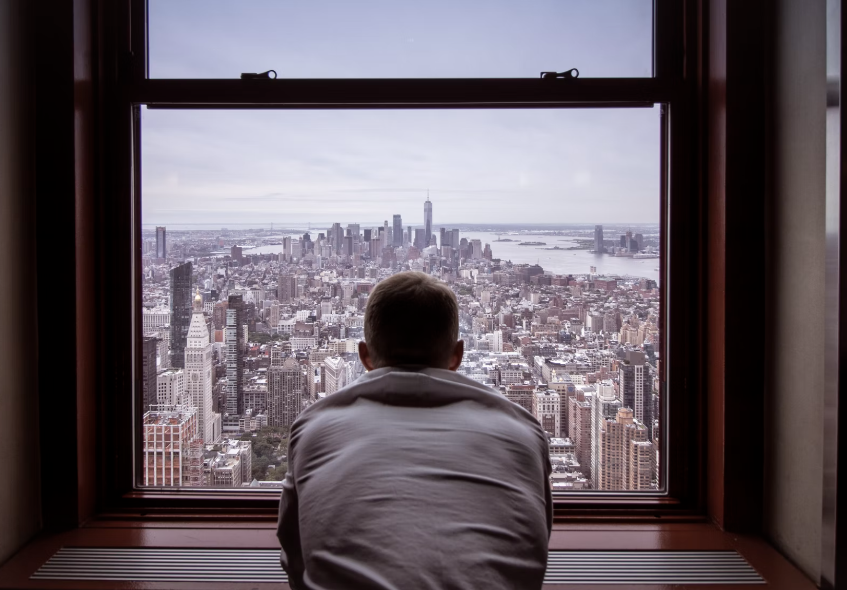 Man sitting and looking out window high above New York City