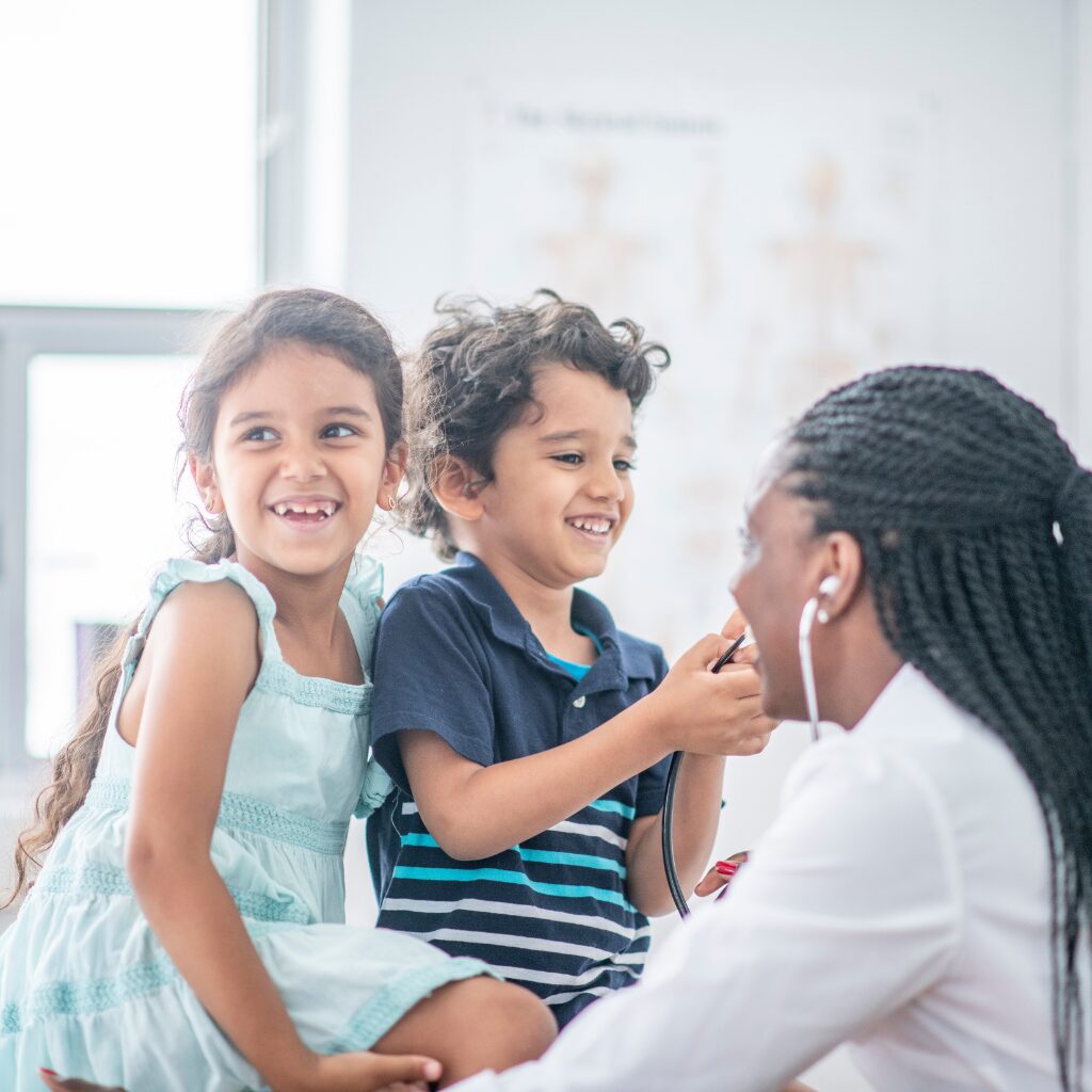 Doctor supporting two children during a medical visit, representing pediatric Long COVID care and awareness.