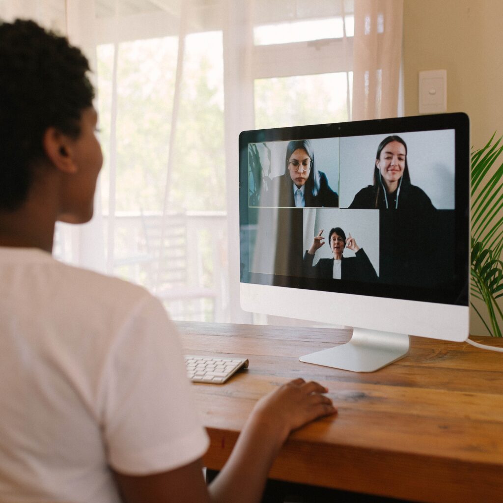 Person at desk joins a Zoom meeting with three others, each in separate video windows on the computer screen.