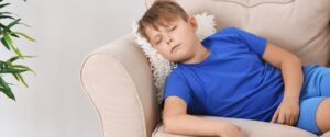 Child resting on a couch, representing the fatigue many children with Long COVID experience.