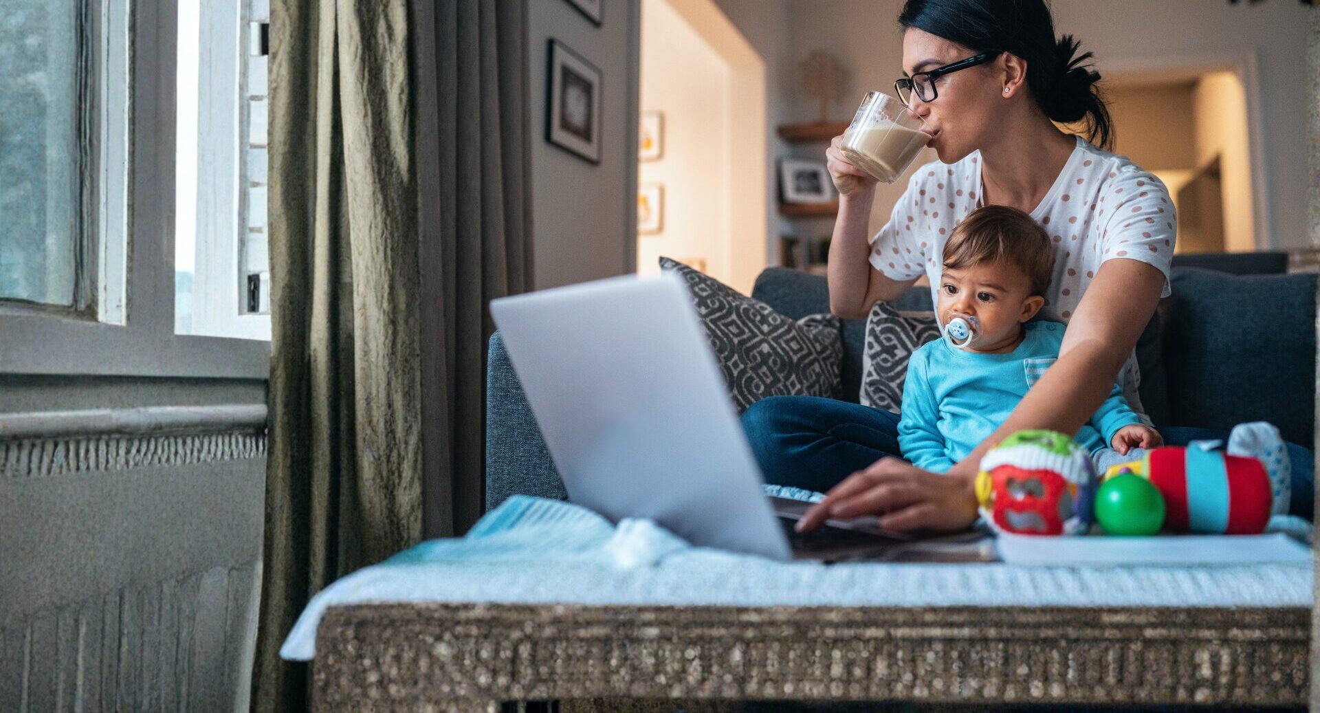 Unrelated parent with a baby on her lap while using a laptop