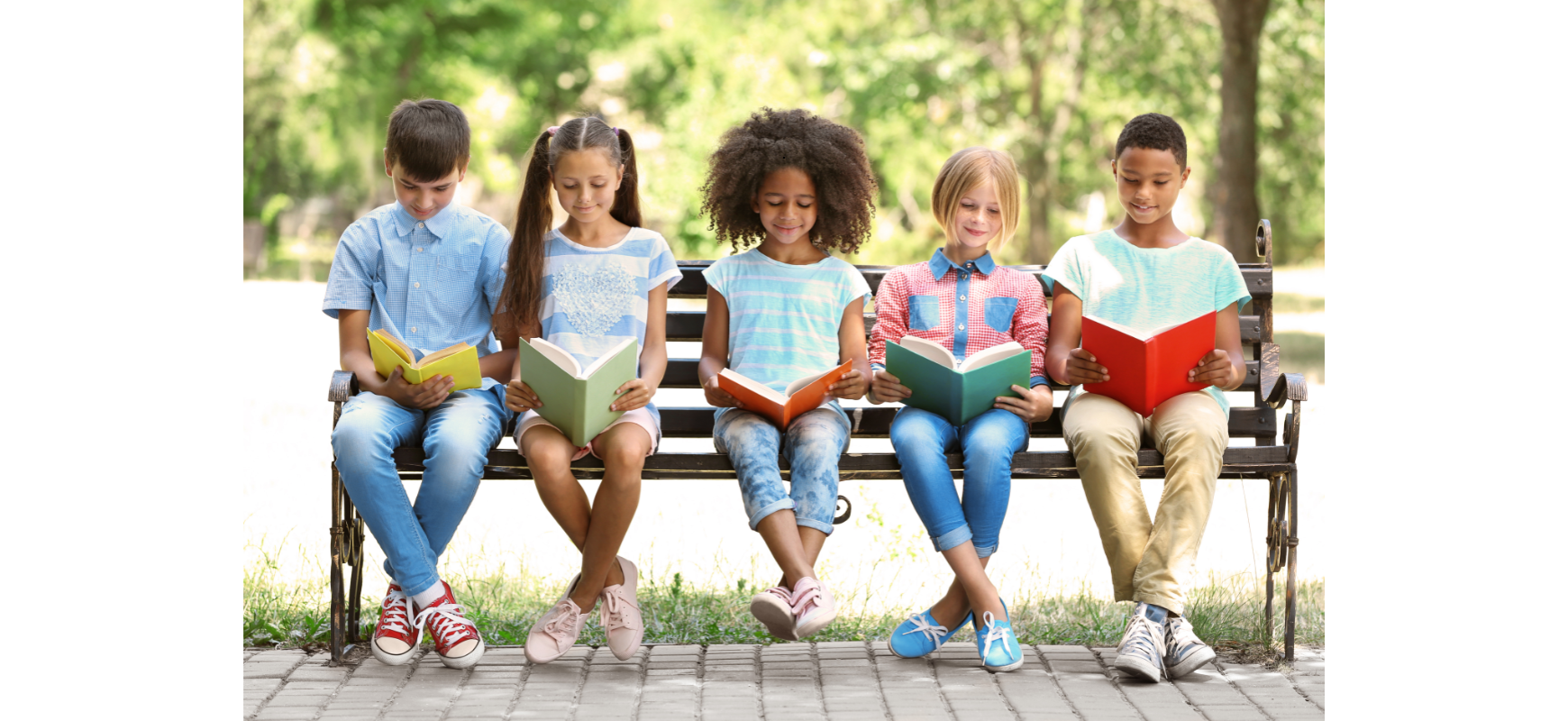 Children reading books together on a park bench