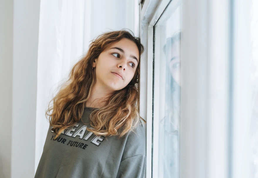 A young person looking out of a window.